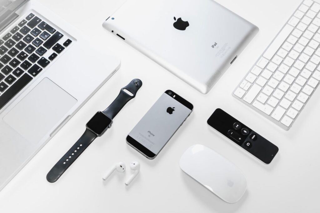 A MacBook, iPad, iPhone, Apple Watch, keyboard, and accessories arranged on a white surface.